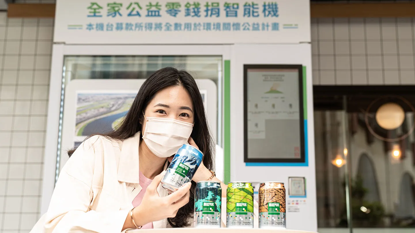 女生於零錢捐智能機前手持看見台灣罐