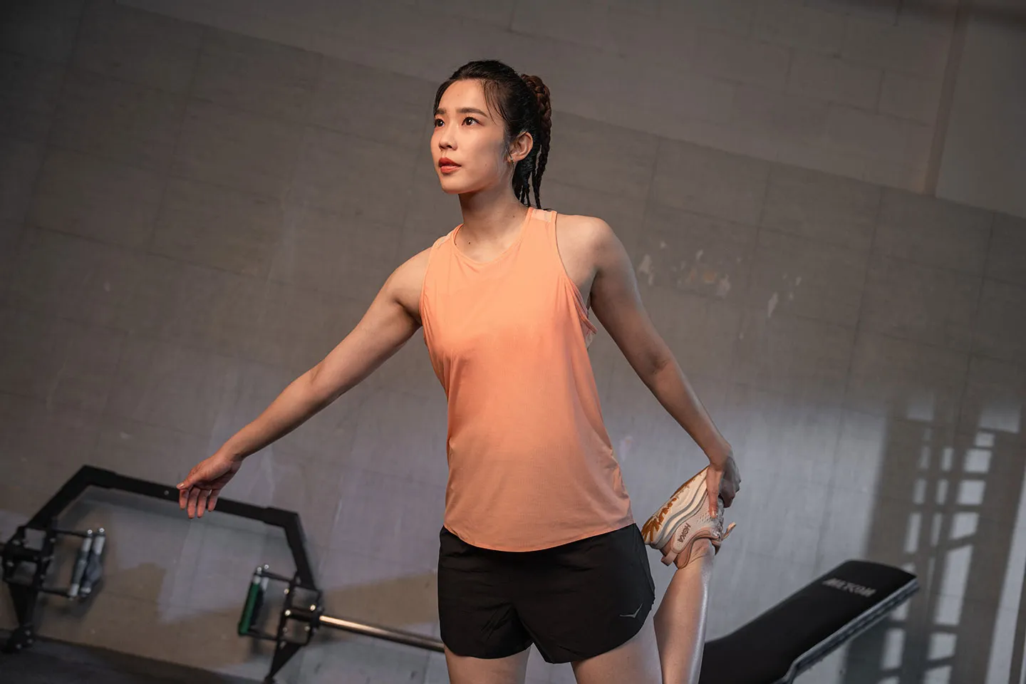 HOKA KOL 身穿橘色背心於健身空間伸展