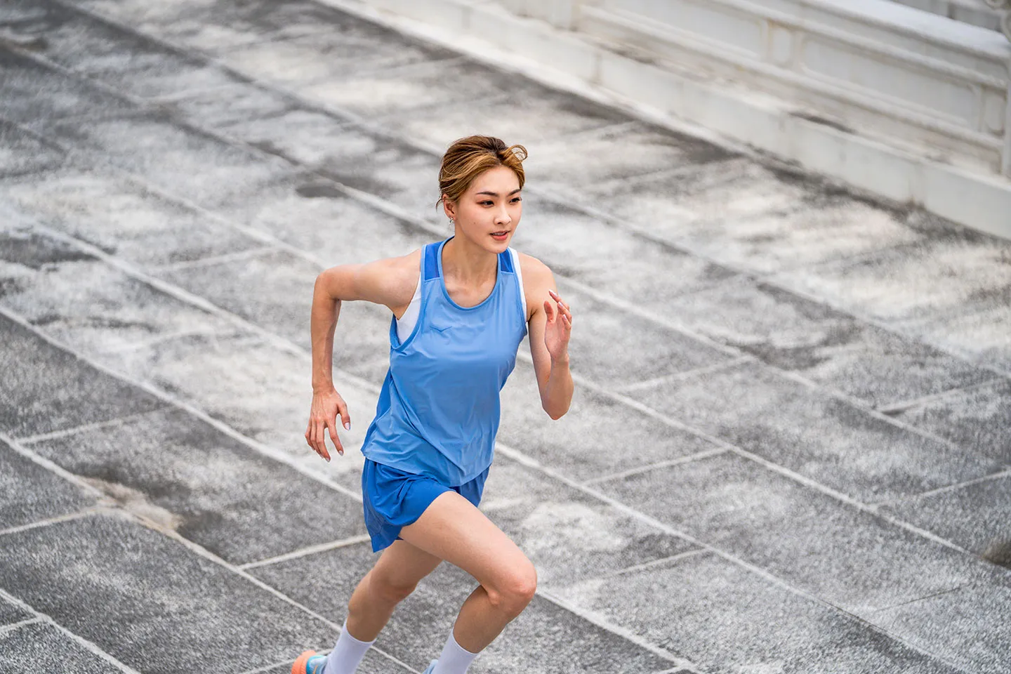 HOKA KOL 身著藍色運動服於戶外階梯跑步