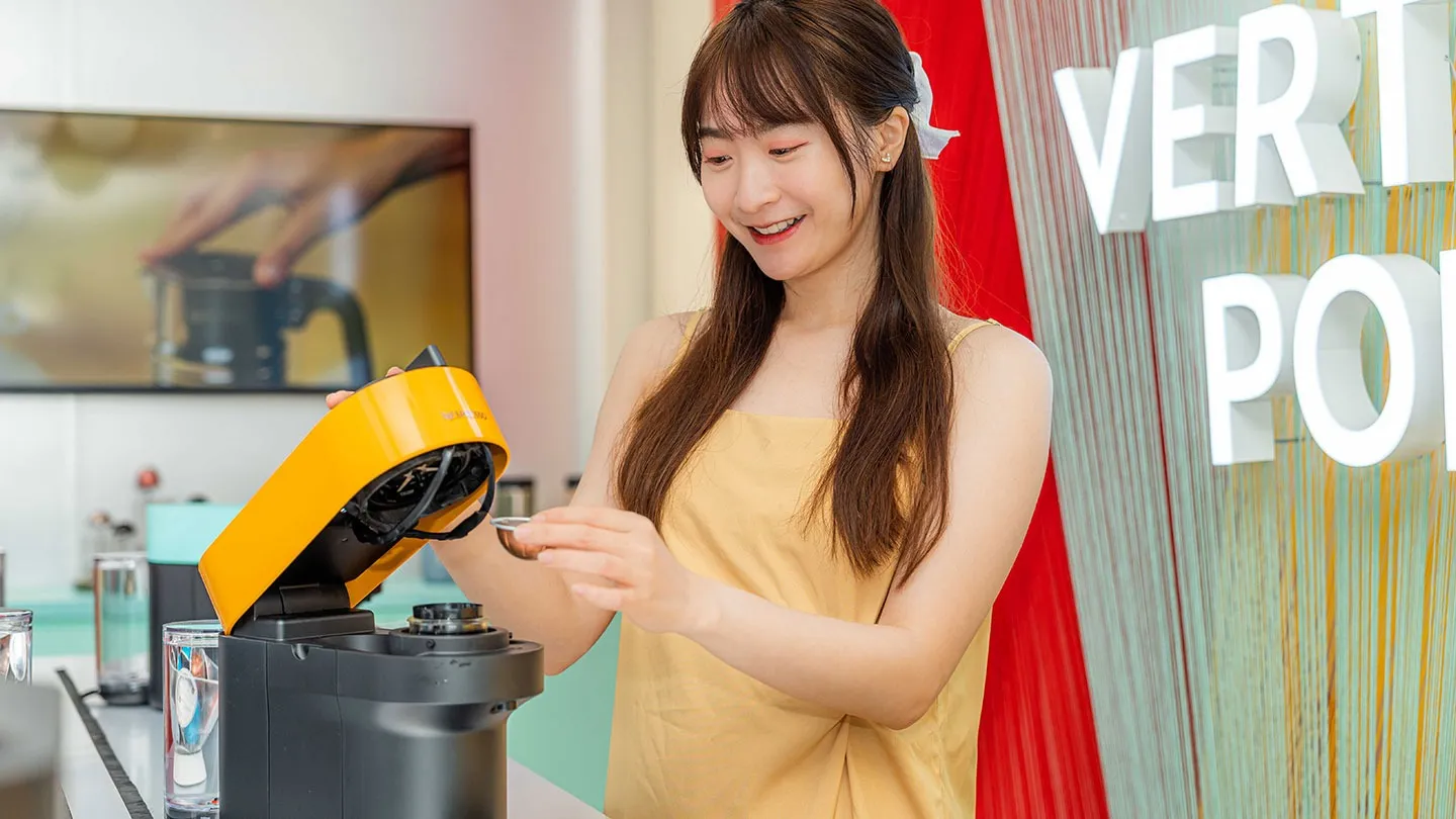 女性 KOL 體驗黃色 VERTUO POP 咖啡機放入膠囊